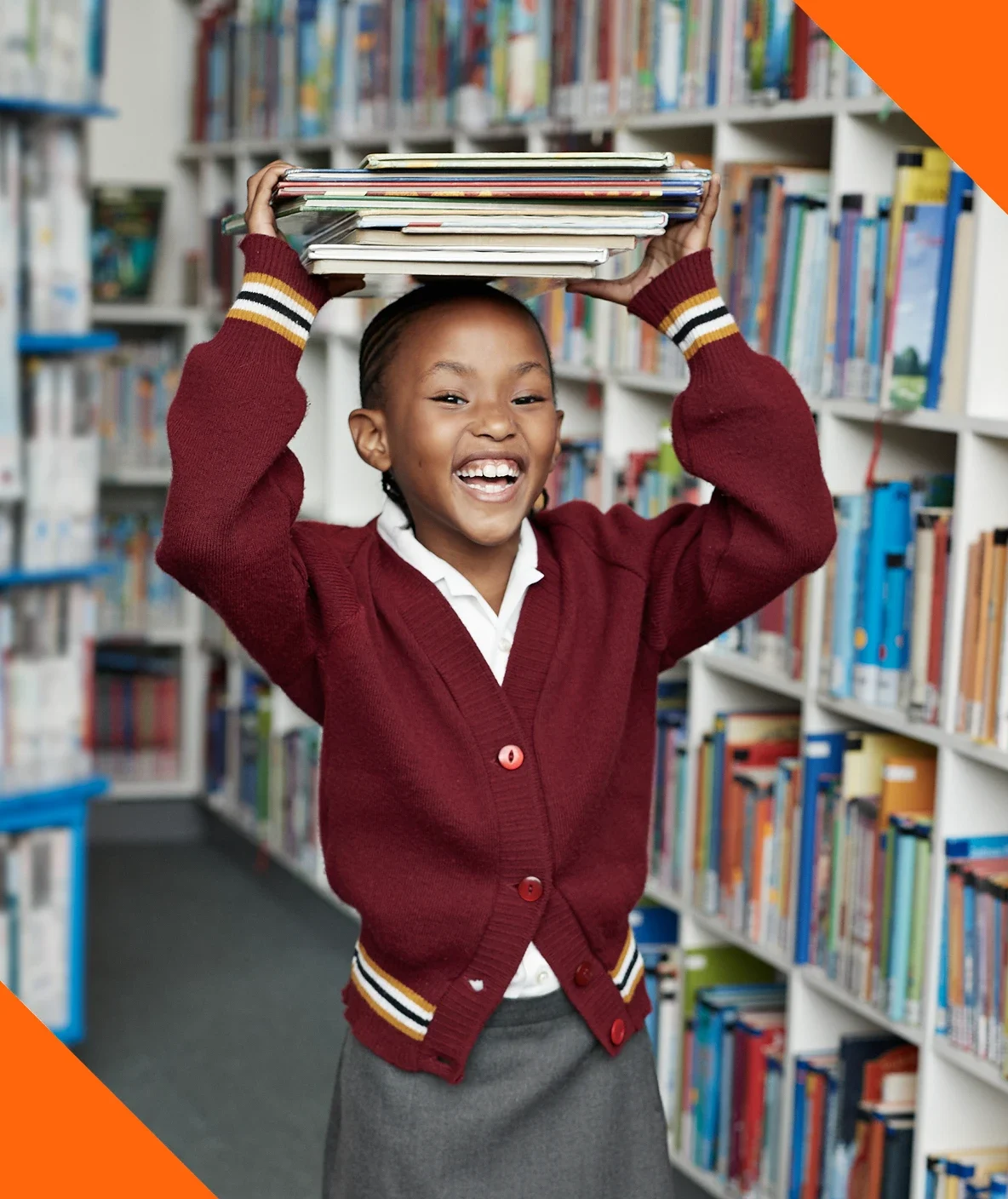 Child carrying books in library.