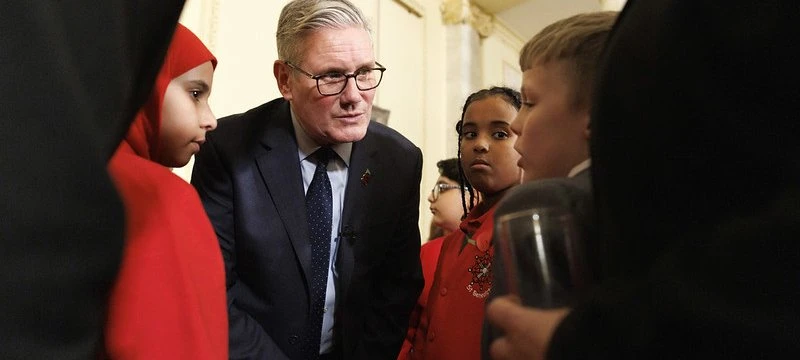 British Prime Minister Kier Starmer speaking with a young person in a formal indoor setting