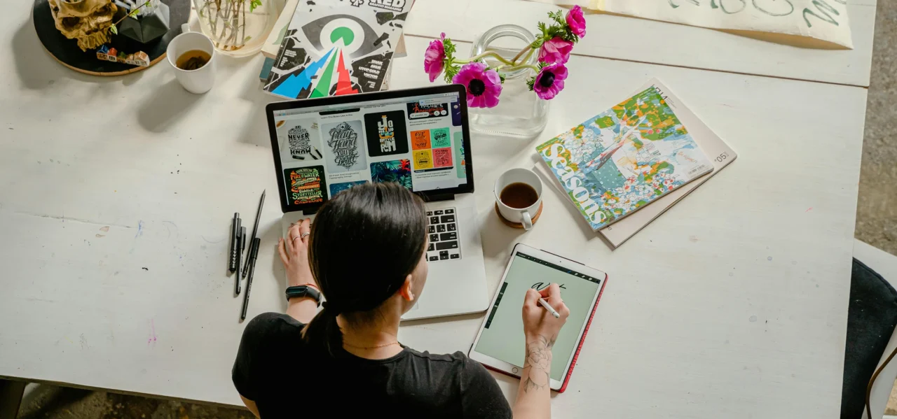 Person working at a desk with a laptop, notebooks and reading materials