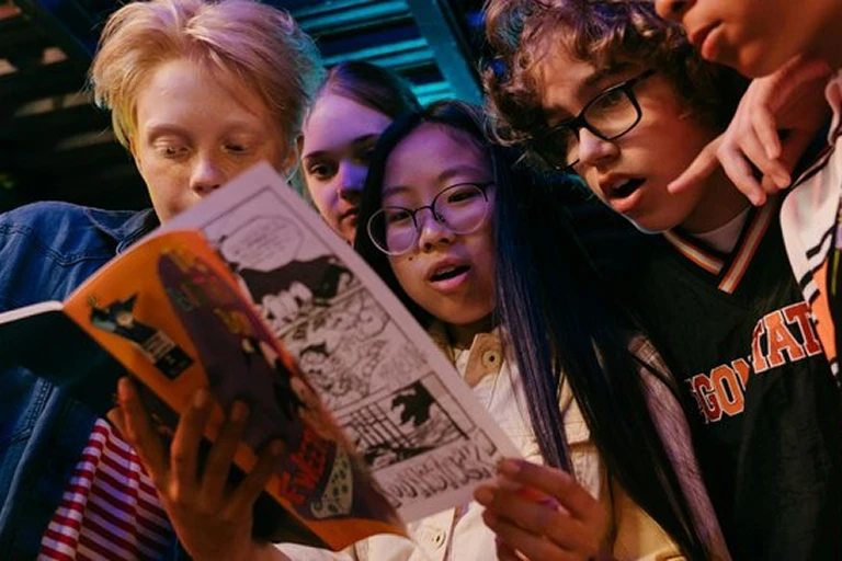 Group of young people reading a comic book together
