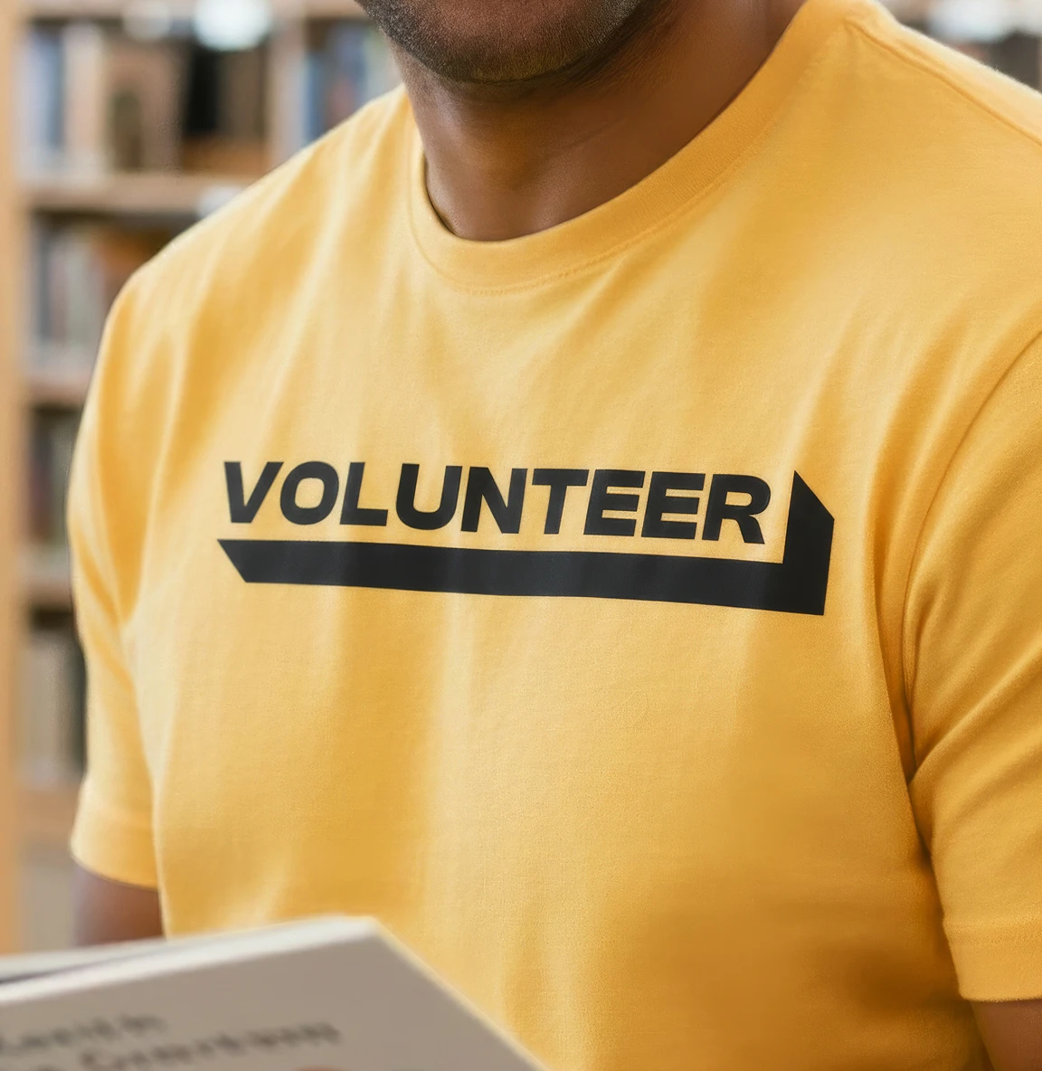 Close-up of a person wearing a yellow T-shirt with the word “Volunteer”