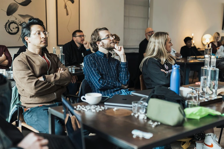 Group of adults seated indoors and listening during a talk or event