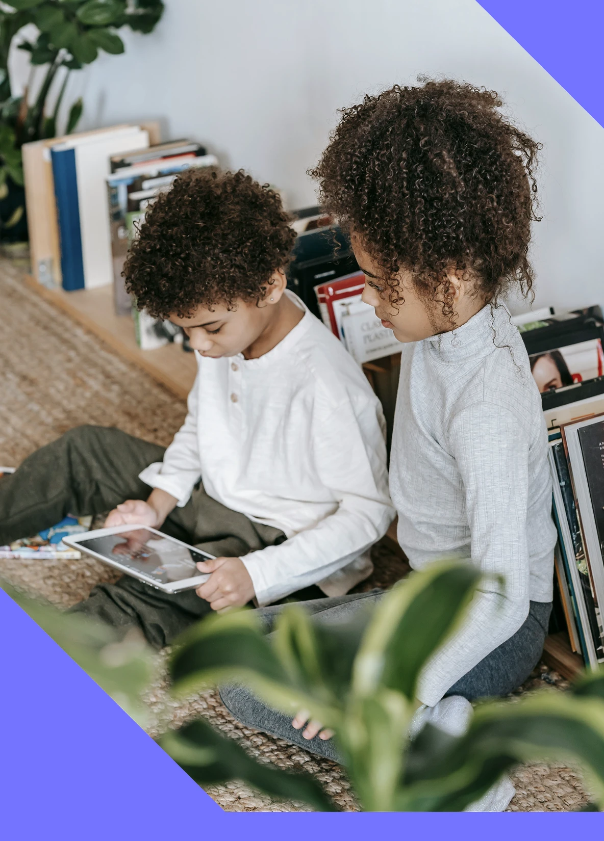 Two young children sitting together and reading a book