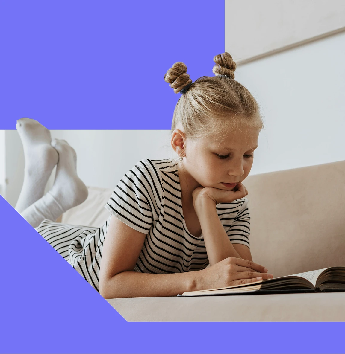 Child lying on a sofa and reading a book