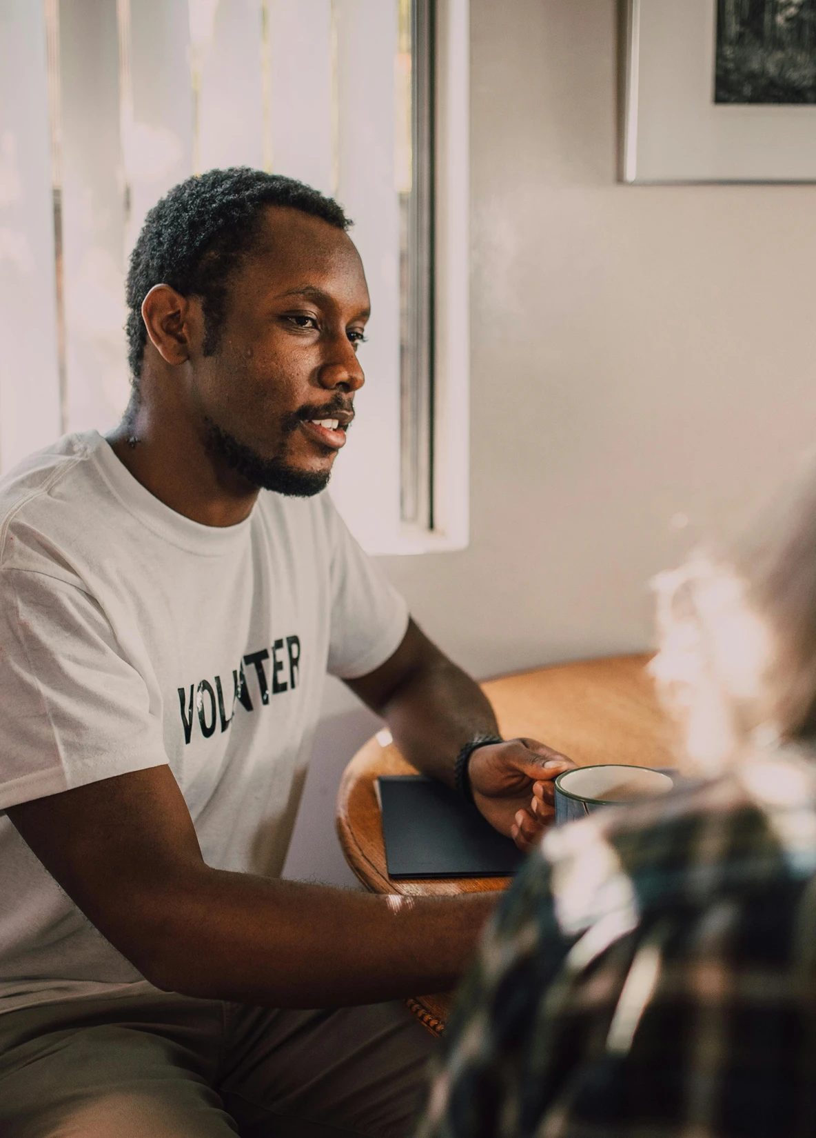 Adult wearing a “Volunteer” T-shirt and reading with a child