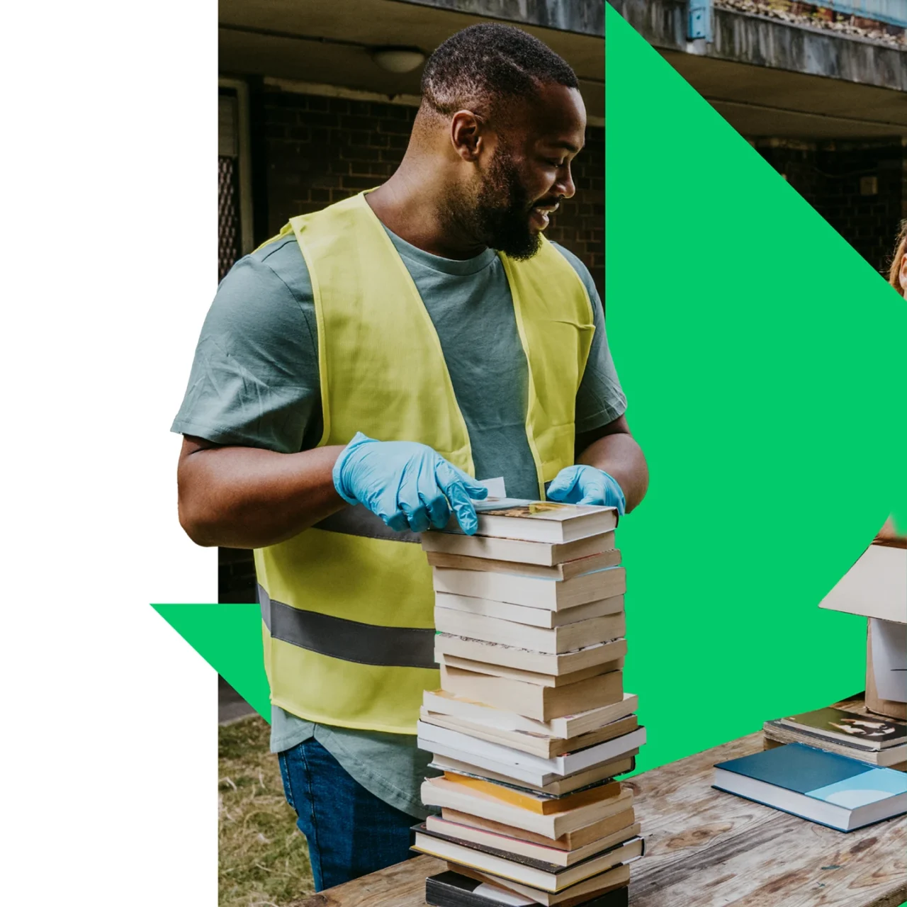 Volunteer wearing gloves and carrying a stack of books