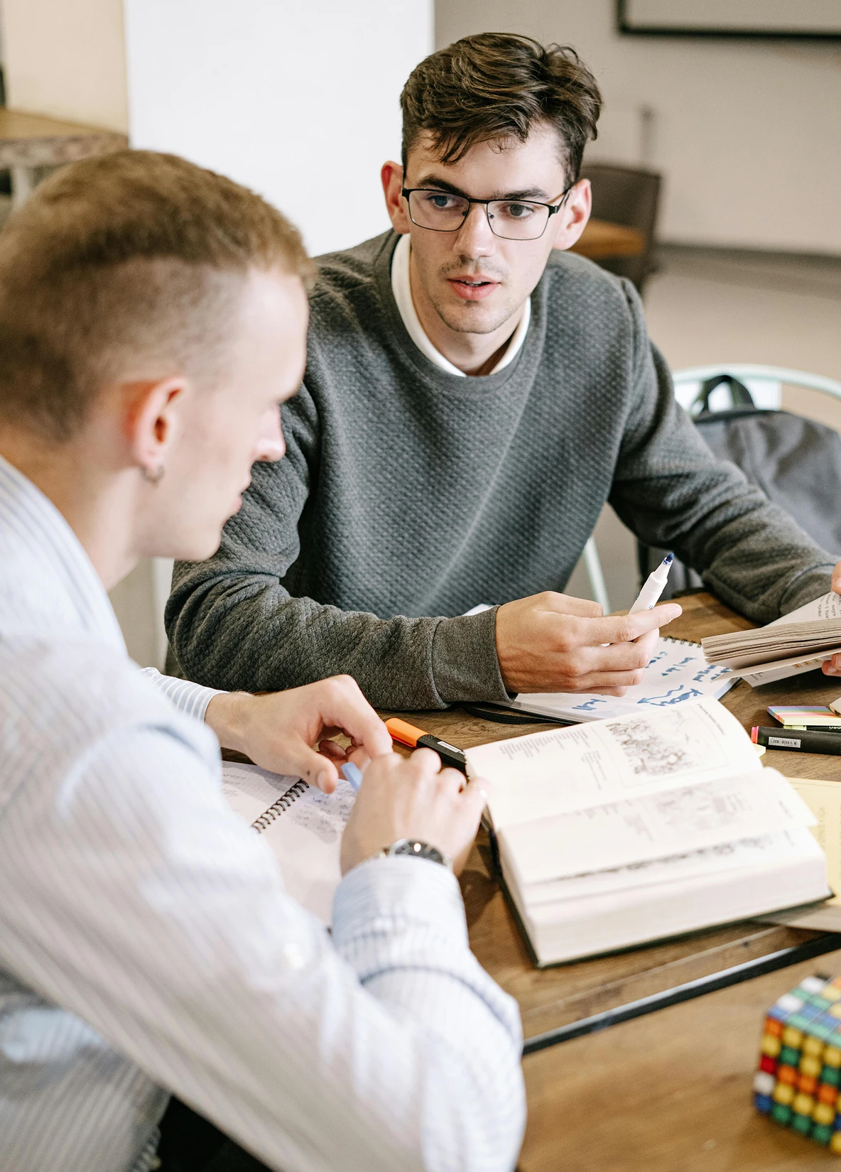 Two adults sitting at a table and studying or reading together