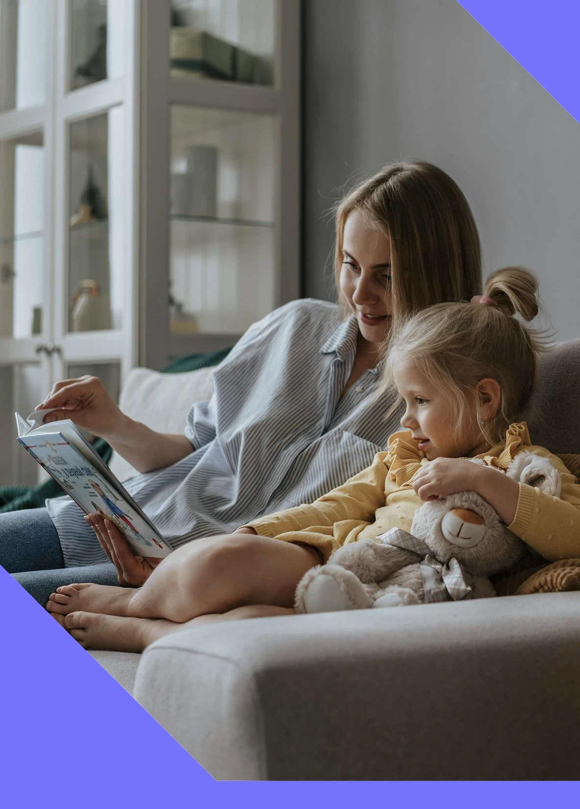 Adult reading a book with a young child seated beside them