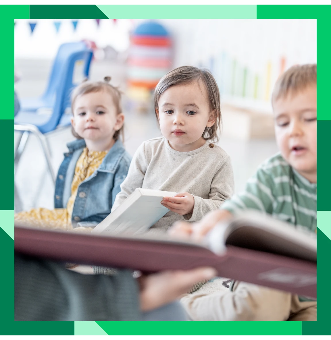 Young children sitting together and looking at a book in a group setting