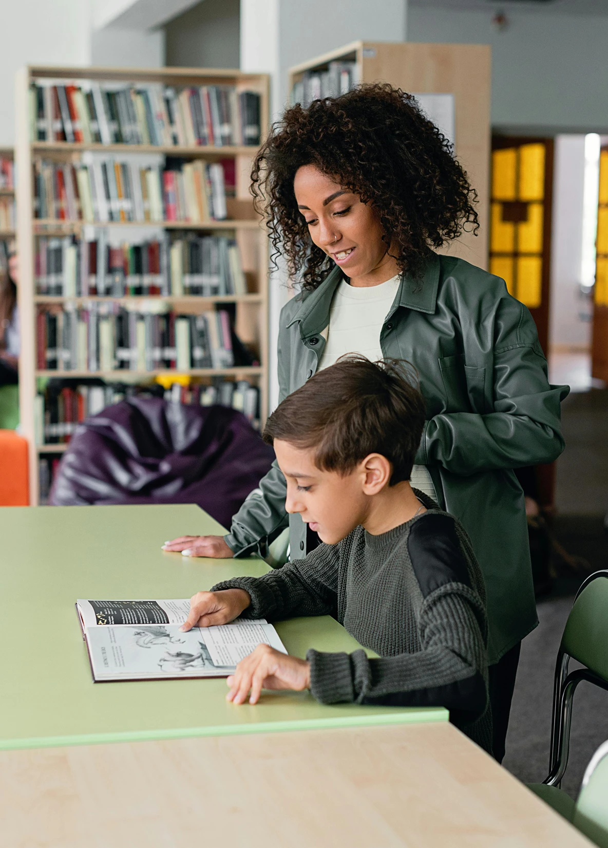 Adult supporting a child with reading or writing at a desk