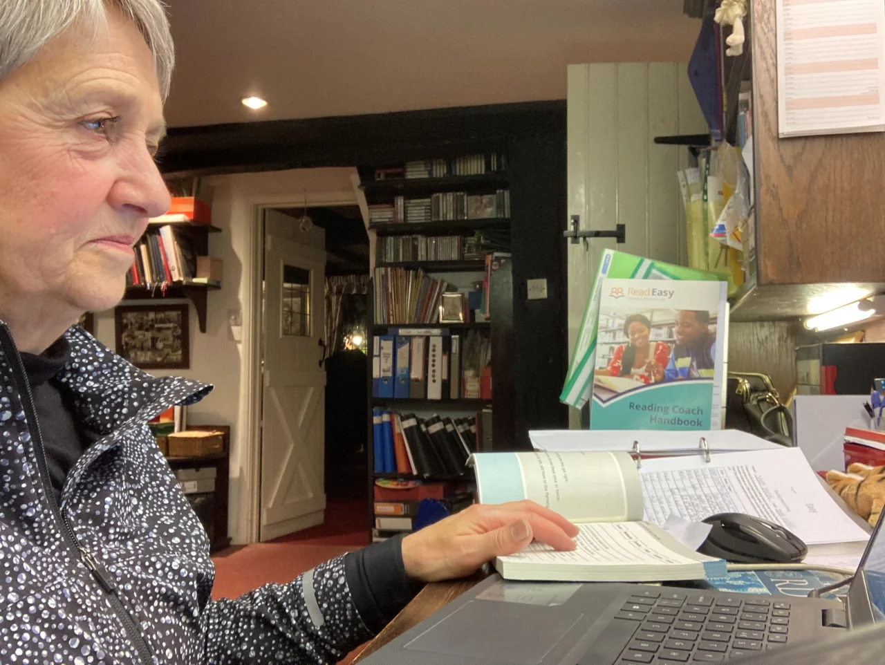 Adult sitting at home and reading a book near a window