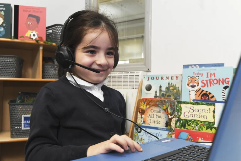 Young child wearing a headset and using a laptop in a classroom setting
