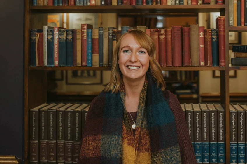 Adult smiling while standing in front of bookshelves