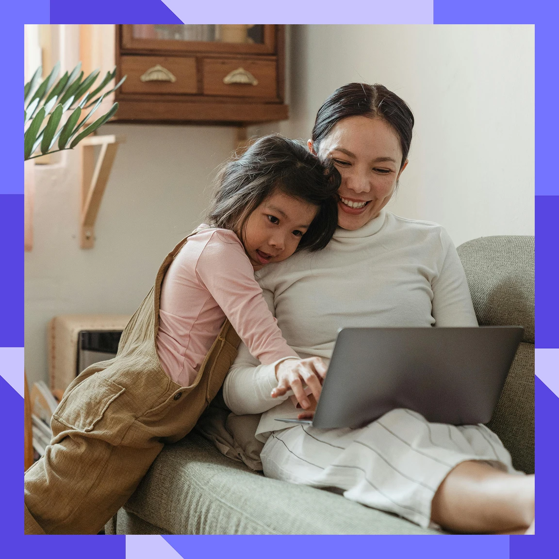 Adult and child sitting on a sofa using a laptop together