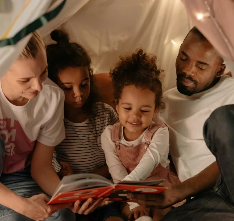 Family sitting together and reading a book inside a blanket fort