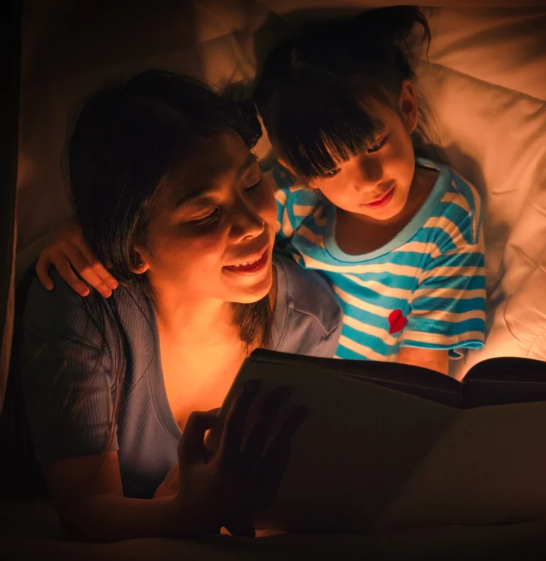 Adult reading aloud to a child using a tablet at bedtime