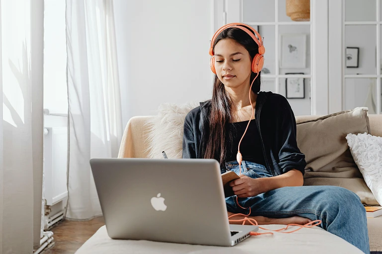 Teenager reading while listening to music on a laptop at home