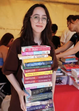 Volunteer holding a large stack of donated books at a community reading event
