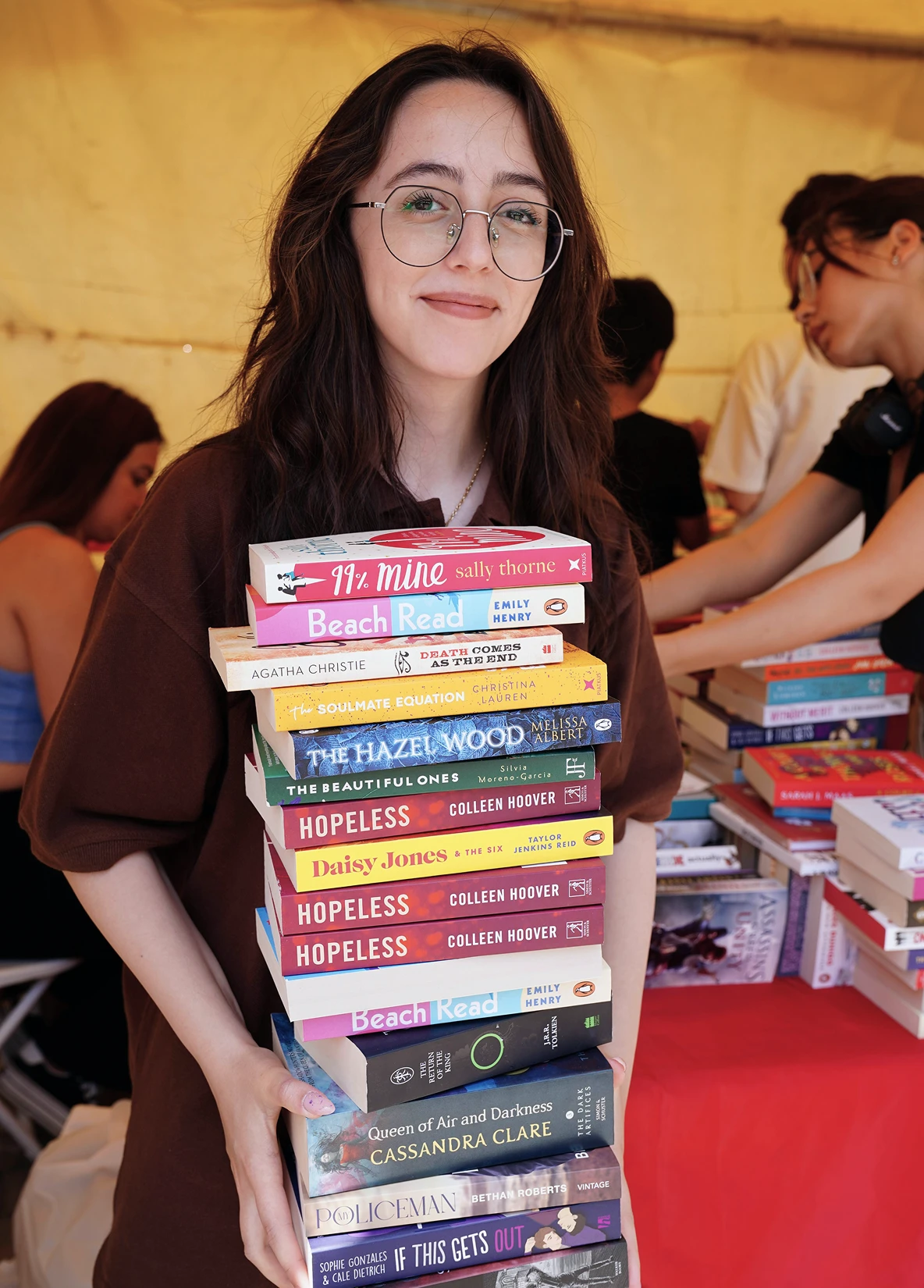 Volunteer holding a large stack of donated books at a community reading event