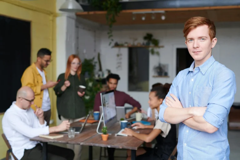 Group of young adults collaborating in a shared workspace, working together around desks