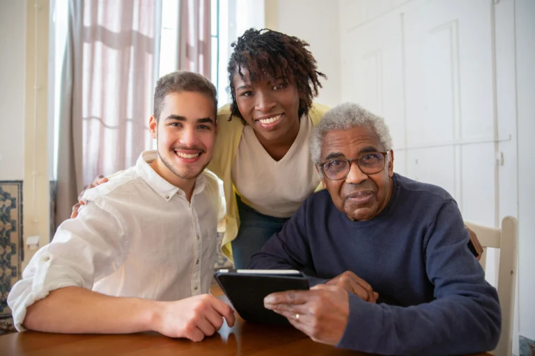Three adults of different ages and backgrounds smiling together while looking at a tablet