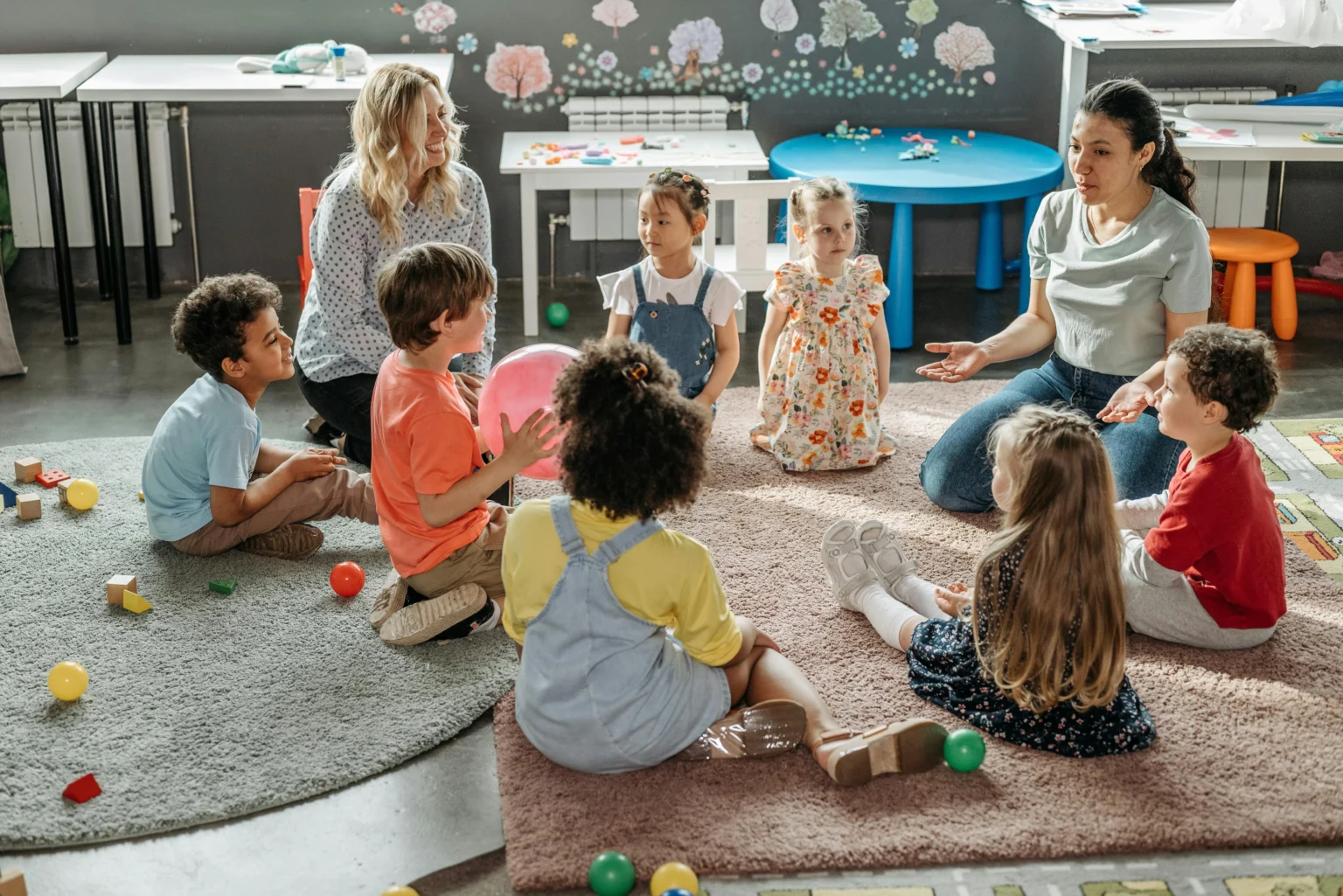 Children sitting in a circle on the floor while an adult leads a shared reading activity