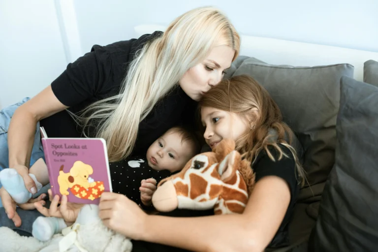 Adult reading a children’s book aloud while sitting closely with two young children