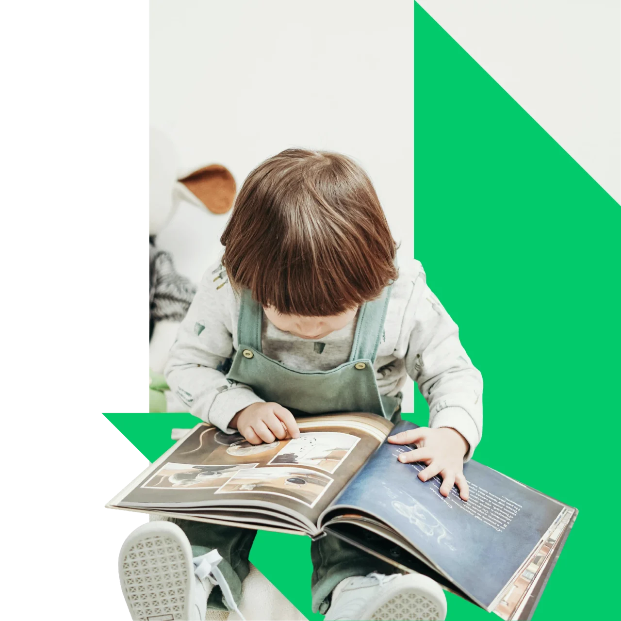 A small toddler sitting on the edge of his bed reading a picture book