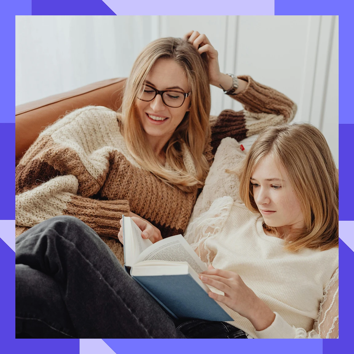 A lady and a teenager sitting on a sofa together reading