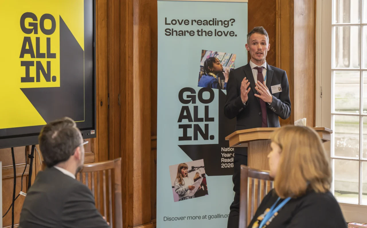Photograph of David Hayman, Director of the National Year of Reading 2026 standing at a lectern addressing a group of people at an event