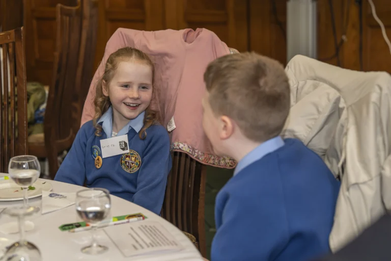 Two young schoolchildren sitting at a table looking interested and engaged