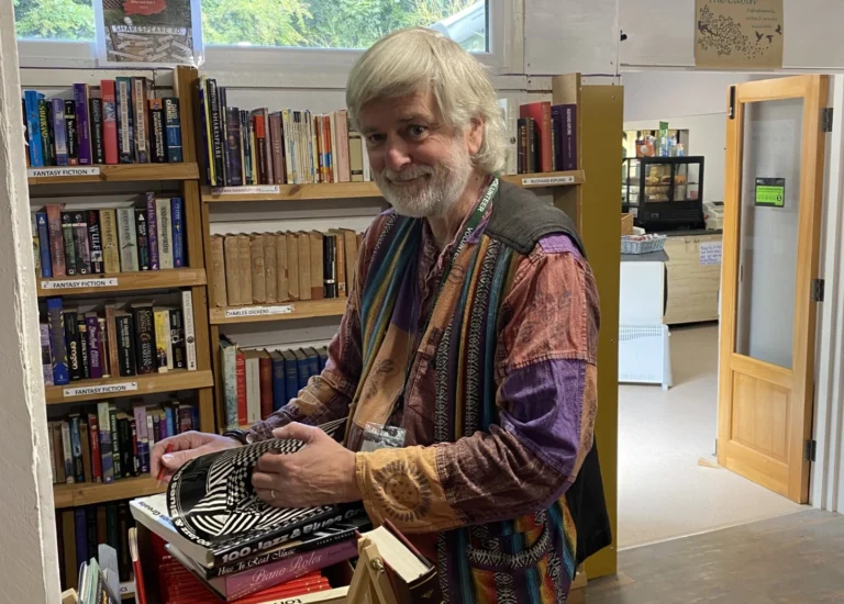 A man smiling, handling books in a bookshop