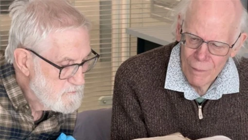 Two older men looking at a book together