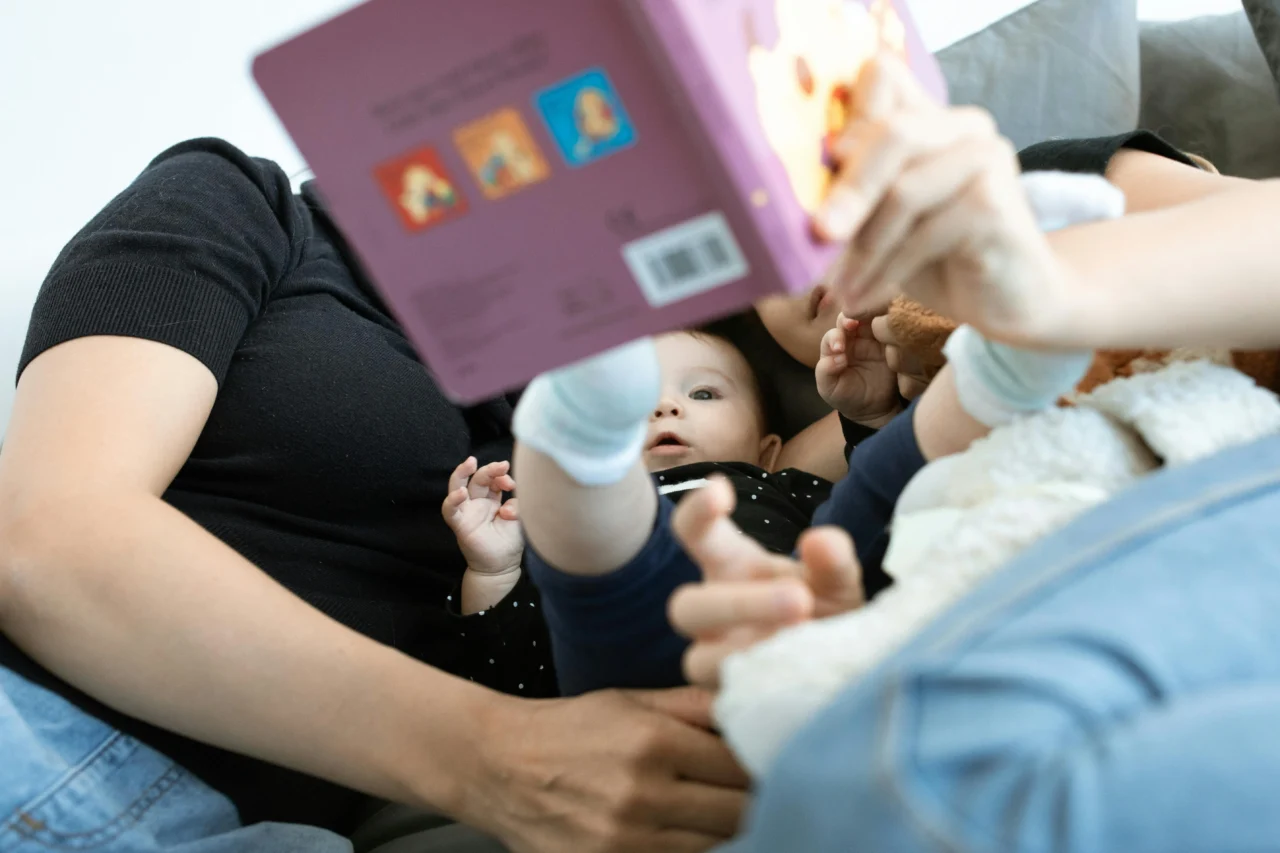 Woman holding small book in front of a baby