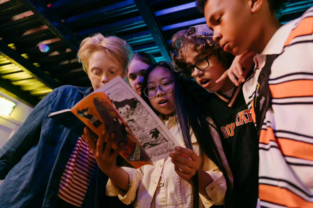 A group of children crowded around and enjoying a comic
